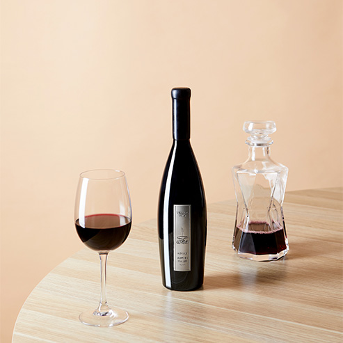 Bottle and glass of a Tempus Two red wine varietal on a wooden table